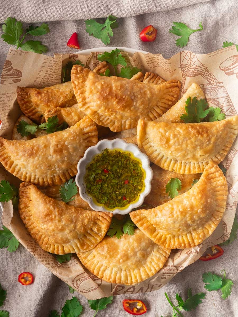 Tuna pastel with chimichurri in a white dish, garnished with fresh cilantro and red chili slices.