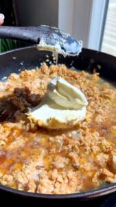 Sautéed ground meat with a dollop of marscapone melting in a sizzling pan.