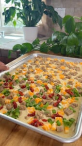 Sheet Pan pancakes with cheese, sausage, sun-dried tomatoes, and green onions in a baking pan.