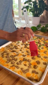 Person brushing oil on sheet pan pancakes.