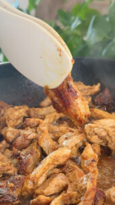 Cooking marinated chicken strips in a skillet with spatula, close-up view.