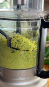 Falafel mixture in food processor with spoonful close-up.