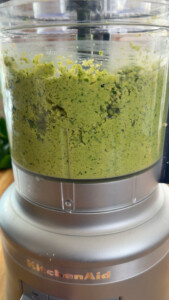Falafel paste blending in KitchenAid food processor close-up.