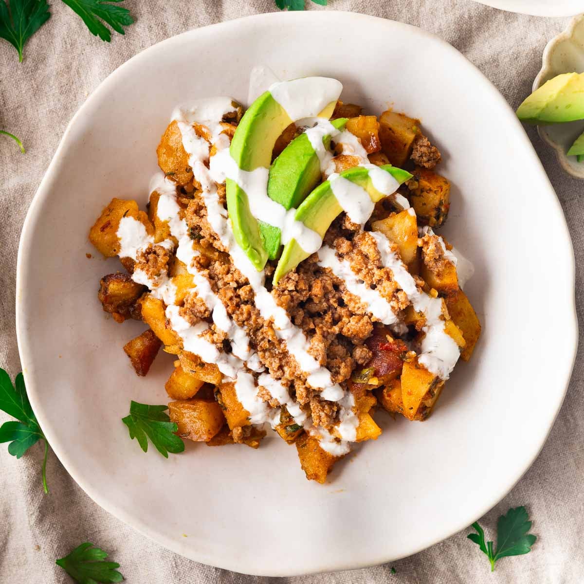 Lebanese potato bowl with seasoned potatoes, ground meat, avocado, and drizzled yogurt sauce.