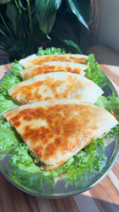Golden-brown quesadillas on a bed of fresh green lettuce on a platter.