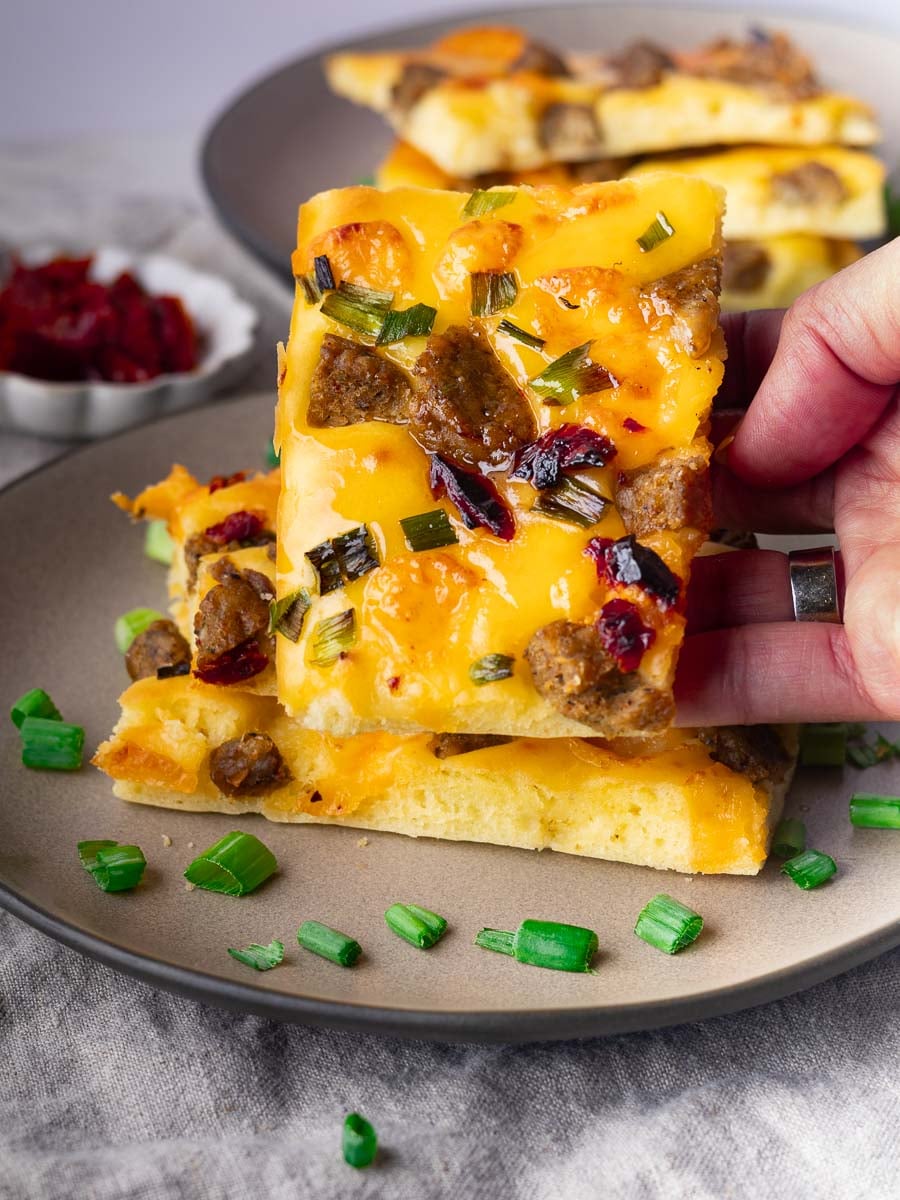 Close-up of sheet pan savory pancakes being lifted from a plate with green onion garnish.