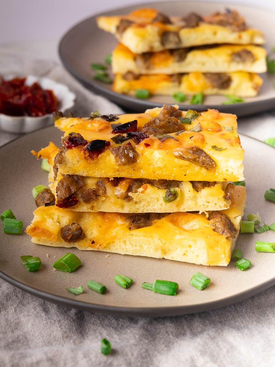 Stacked sheet pan savory pancakes with meat and green onions on a beige plate.