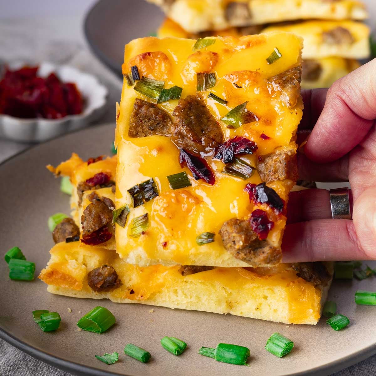 Sheet pan savory pancakes with sausage, cranberries, and herbs on a plate.