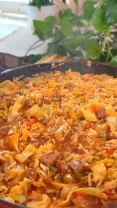 Rice with cabbage, other vegetables and chunks of meat in a skillet.