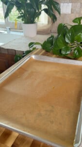 Baking sheet with parchment paper on wooden countertop.