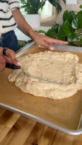 Spreading batter on baking tray with spatula.