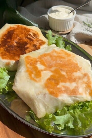 Chicken Caesar falafel crunchwrap with creamy dipping sauce on a silver platter.