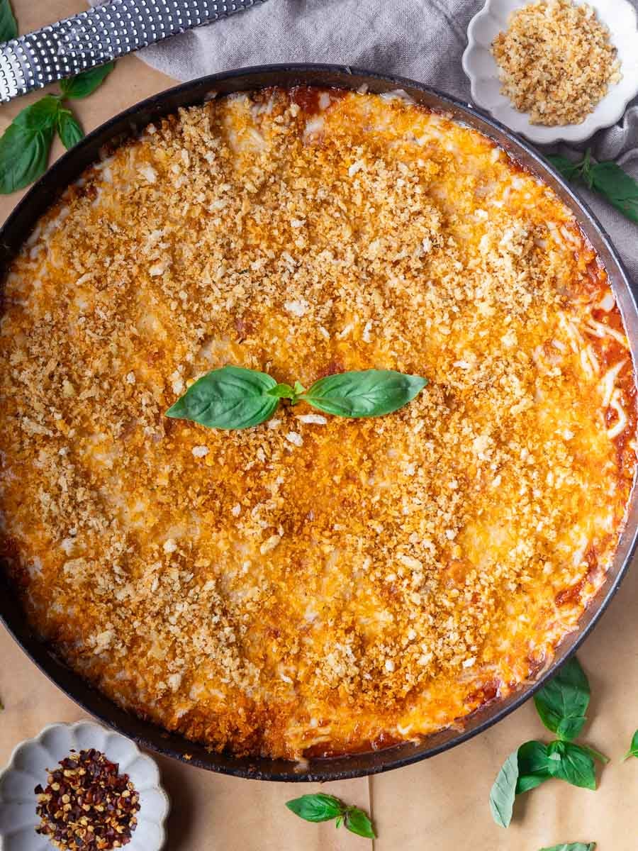 Cheesy gnocchi chicken parm with fresh basil garnish on a grey cloth background.