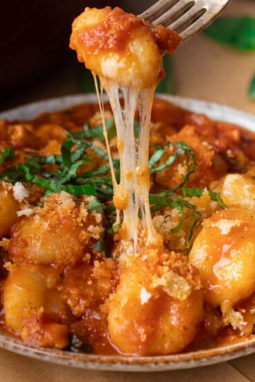 Cheesy gnocchi chicken parm with fresh basil and breadcrumbs on a fork.