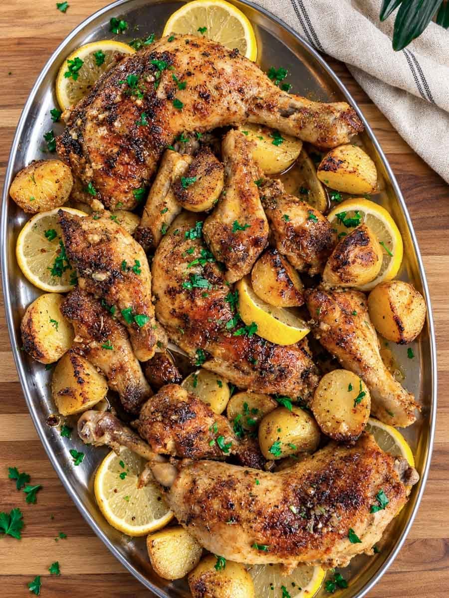 Lebanese garlic chicken and potatoes, garnished with herbs on a platter.