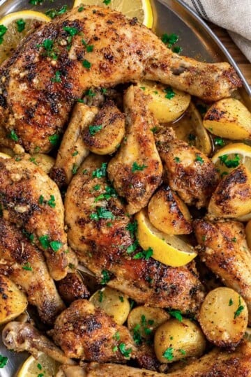 Lebanese garlic chicken and potatoes, garnished with herbs on a platter.