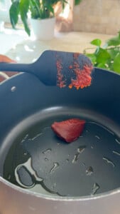 Tomato paste in a saucepan with a spatula scraping the pan