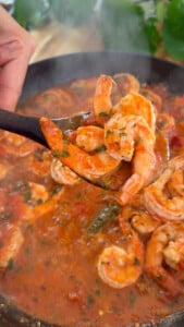 Fresh shrimp cooking in a tomato and herb sauce in a skillet.