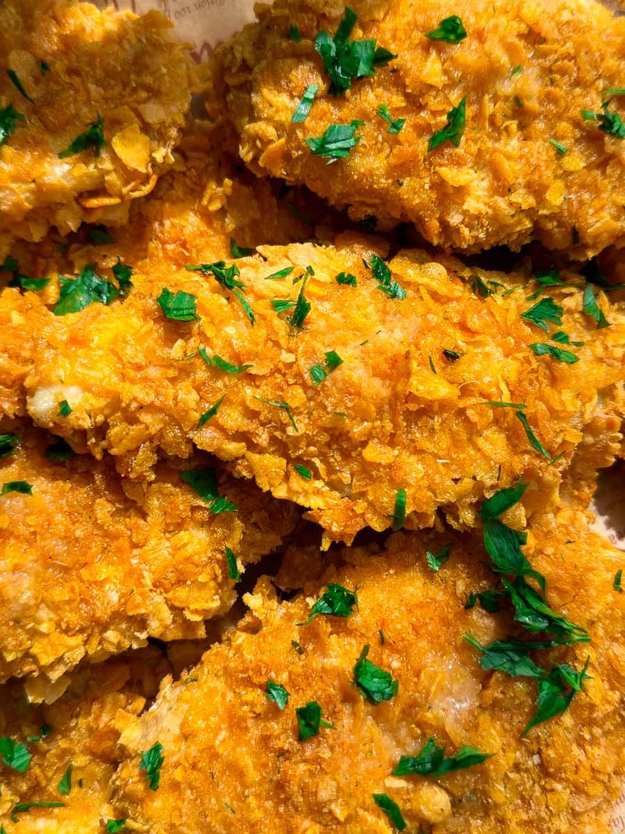 Crispy baked chicken tenders topped with chopped parsley.