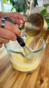 Whisking eggs in a glass measuring cup, pouring liquid.
