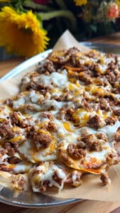 Cheesy beef potatoes topped with melted cheese and ground meat on a baking sheet.