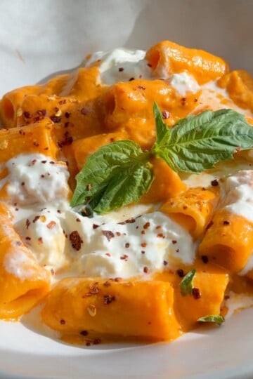 Pasta with creamy veggie sauce, ricotta cheese, chili flakes, and fresh basil in a bowl