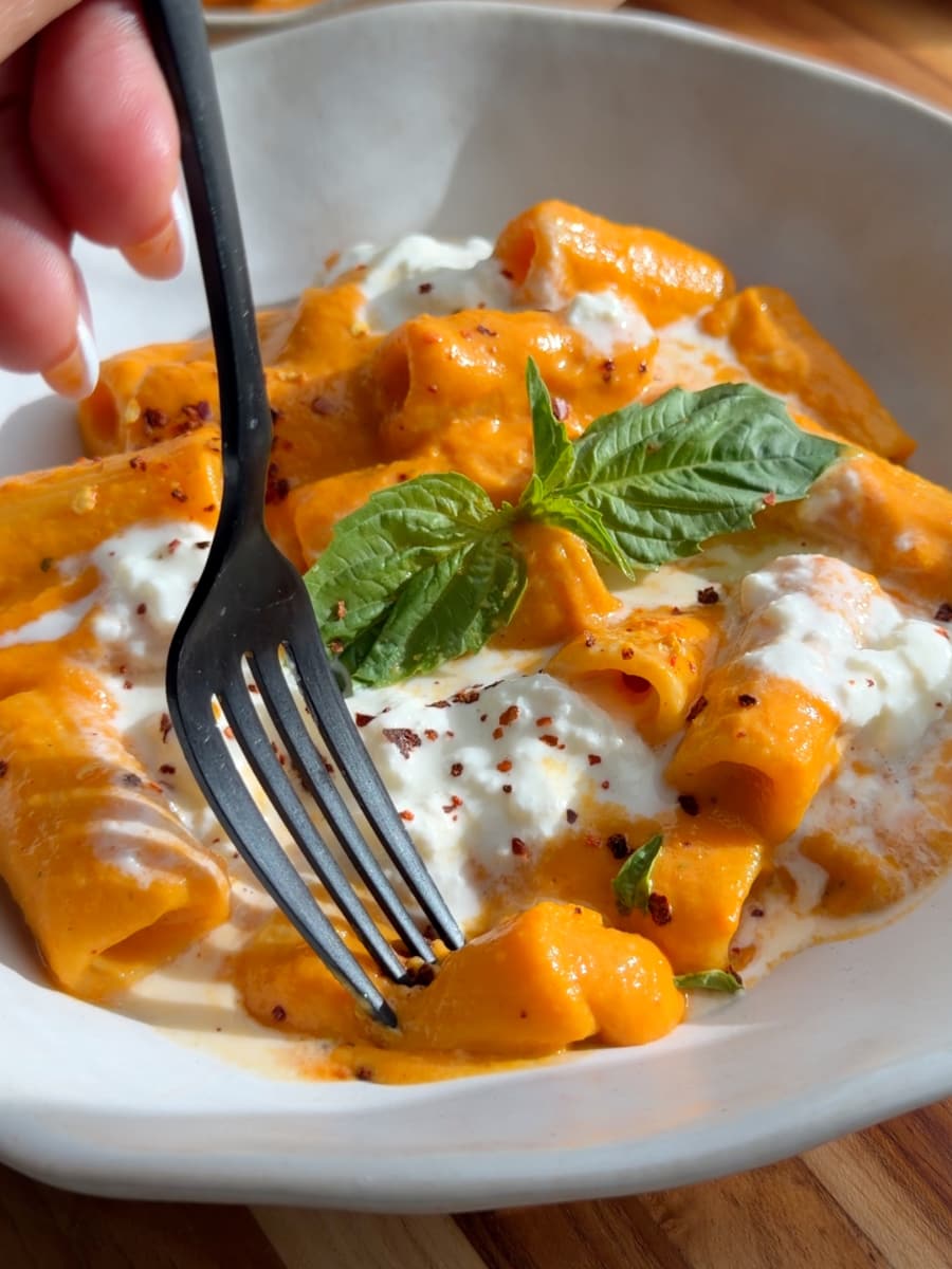 Pasta with creamy veggie sauce, ricotta cheese, red pepper flakes, and basil in a bowl