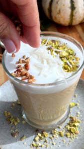 Pumpkin sahlab being topped with pistachios and coconut