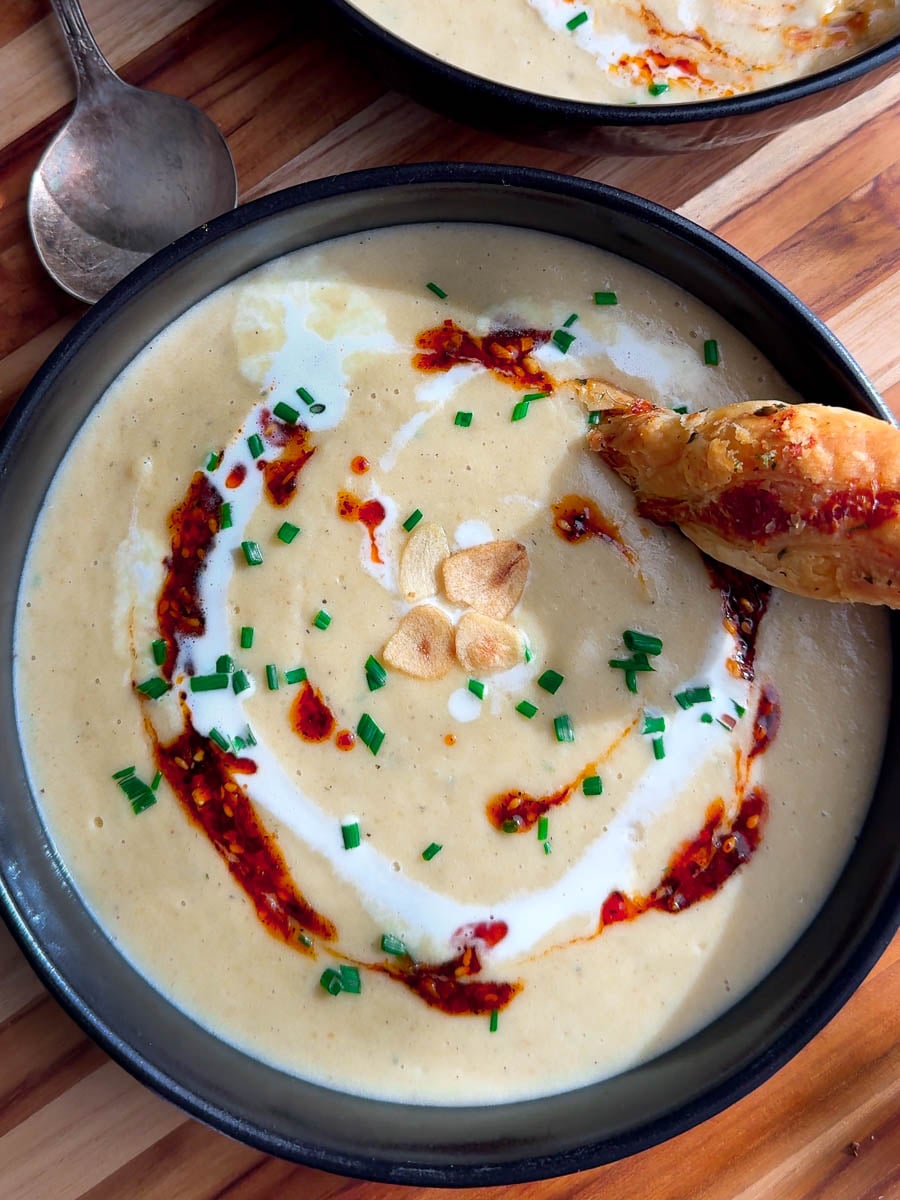 Creamy roasted garlic soup with chives, chili oil, cream, and garlic chips.